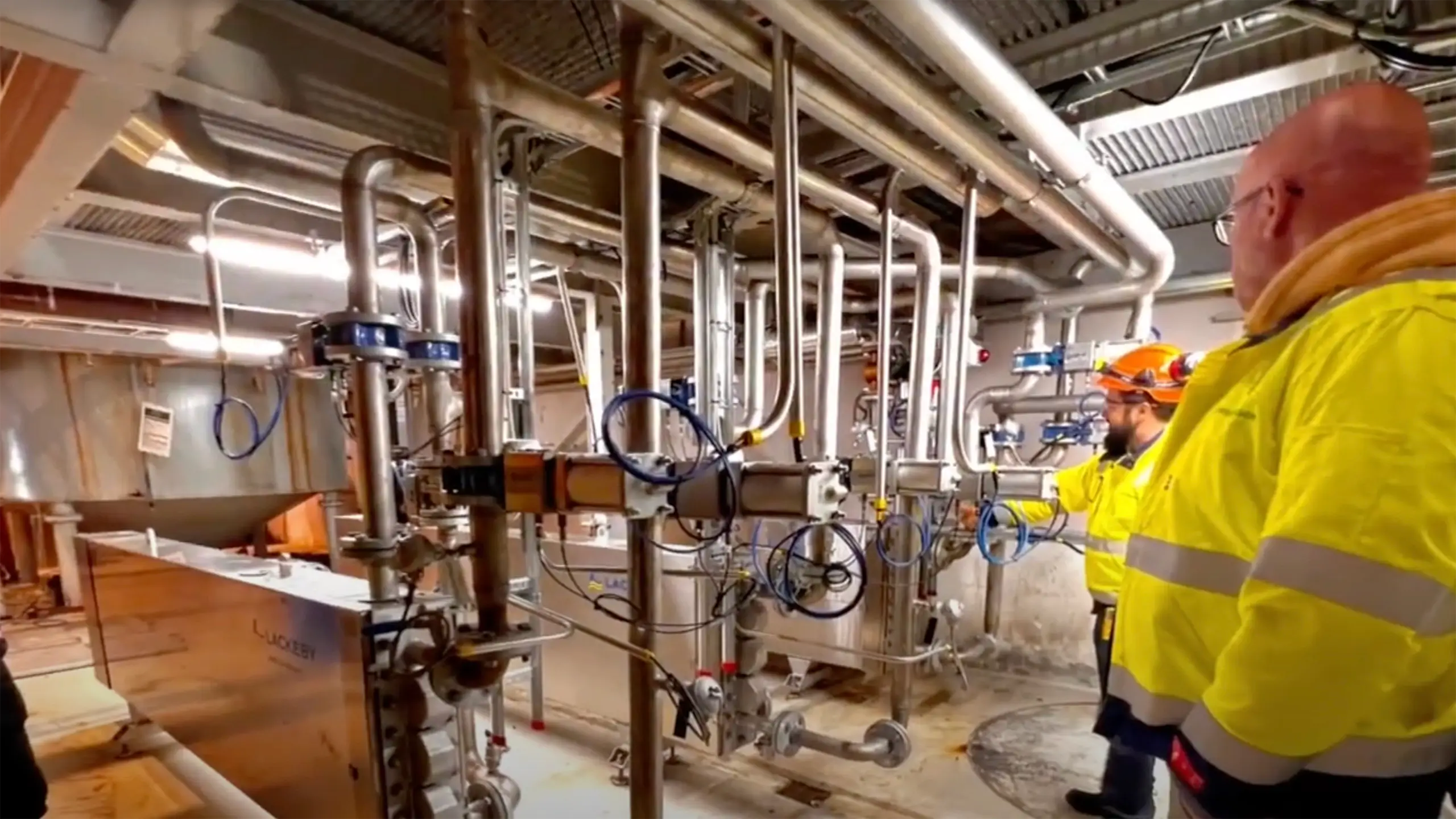 Arbeidere i synlighetstøy inne i et renseanlegg.