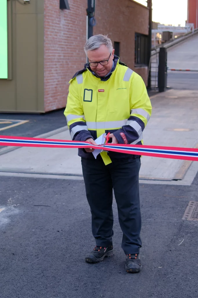 Johnny Sundby i synlighetstøy klipper et bånd for å markere åpningen av FREVARs nye vektstasjon.
