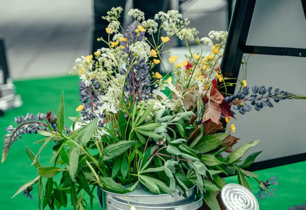 En vannkanne med forskjellige blomster og blader