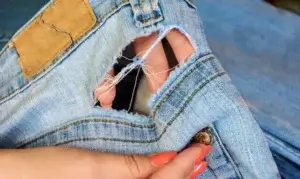 Sorteringsveileder for tekstiler, en jeans med hull.